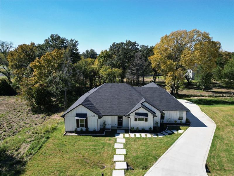 View of front facade featuring roof with shingles, board and batten siding, and a front yard View of front facade featuring roof with shingles, board and batten siding, and a front yard