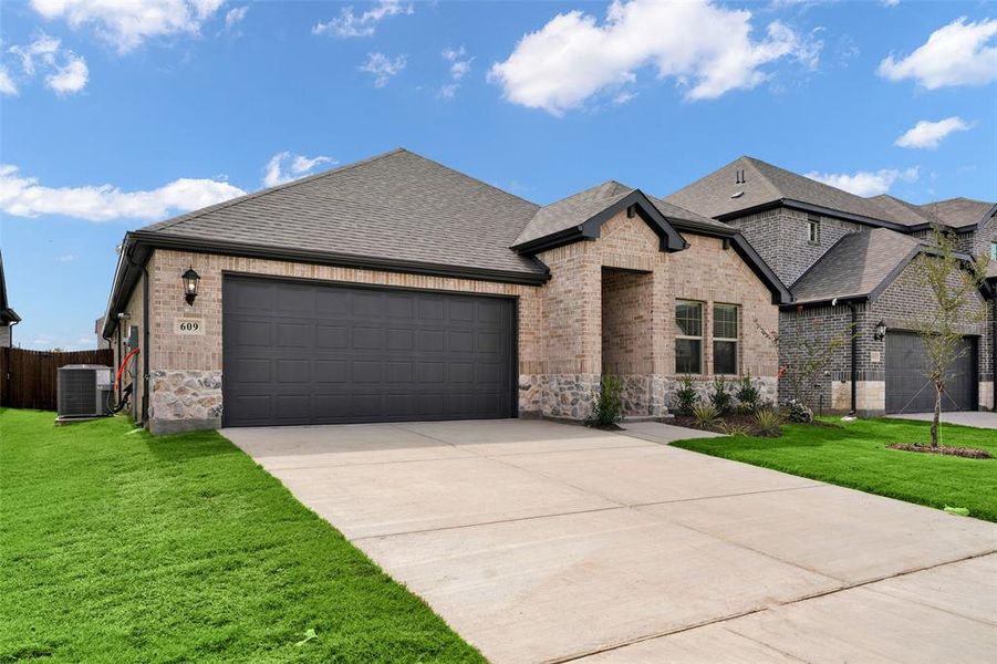 French country home with a shingled roof, brick siding, a garage, and concrete driveway French country home with a shingled roof, brick siding, a garage, and concrete driveway