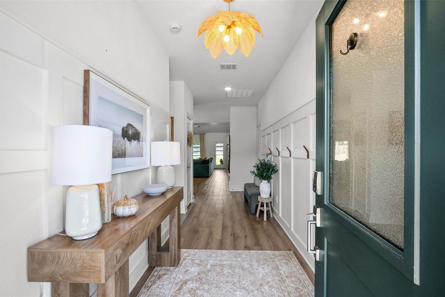 Step inside to a bright and welcoming entryway featuring stylish wall paneling, warm wood-look flooring, modern lighting, and thoughtfully selected finishes that create a beautiful first impression.