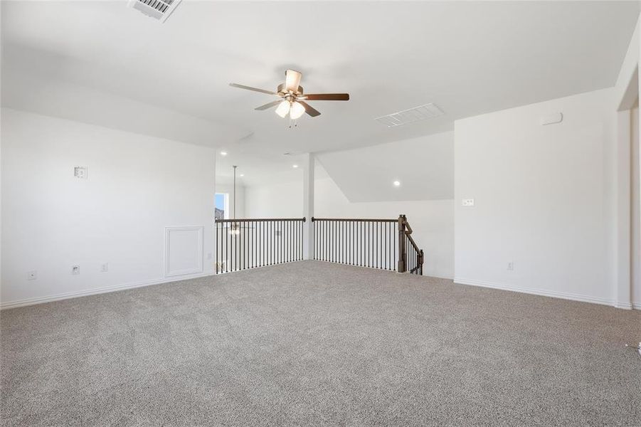 Carpeted spare room with a ceiling fan and baseboards