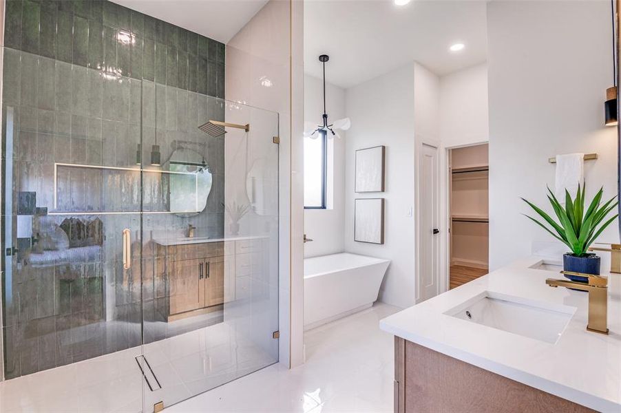 Bathroom featuring a spacious closet, a freestanding tub, double vanity, a stall shower, and recessed lighting Bathroom featuring a spacious closet, a freestanding tub, double vanity, a stall shower, and recessed lighting