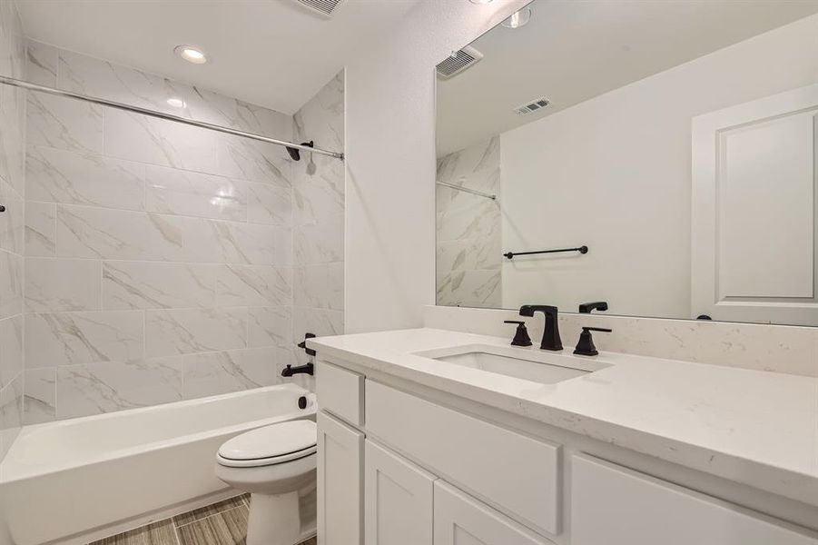 Full bathroom featuring tiled shower / bath, vanity, and toilet