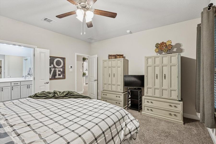 Primary bedroom featuring light carpet, a ceiling fan, connected bathroom, and baseboards Primary bedroom featuring light carpet, a ceiling fan, connected bathroom, and baseboards