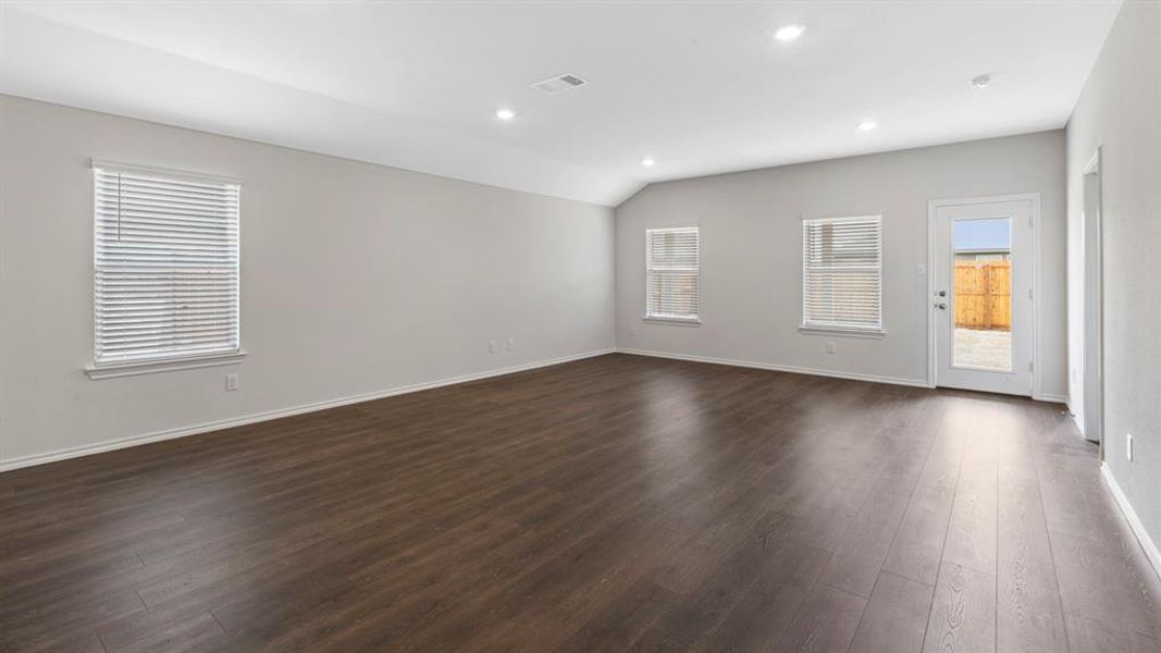Empty room with dark wood-style flooring, recessed lighting, and vaulted ceiling