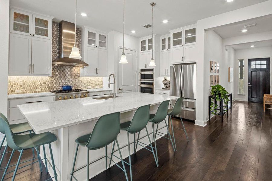 Kitchen featuring visible vents, a sink, decorative backsplash, stainless steel appliances, and wall chimney exhaust hood