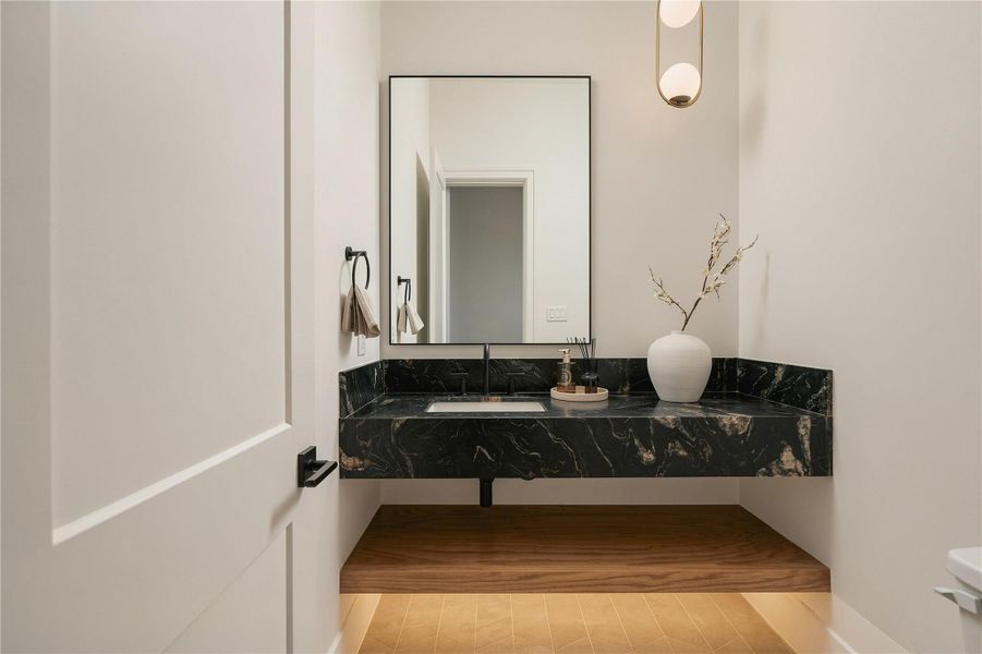 A powder room designed as its own moment, where a floating vanity wrapped in Titanium Quartzite brings drama and sculptural presence to the compact space.