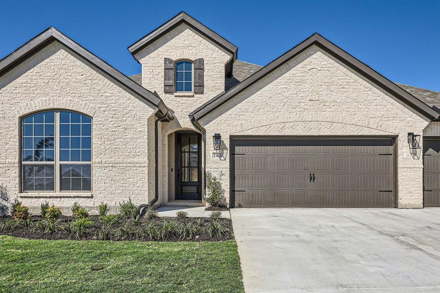 French country style house featuring a garage and a front lawn