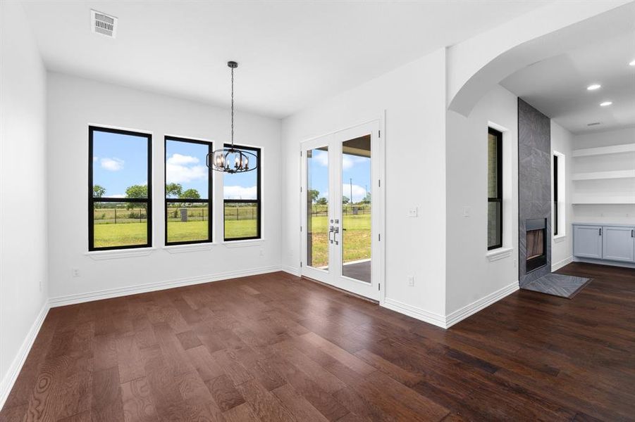 Empty room featuring dark wood-style flooring, arched walkways, a chandelier, recessed lighting, and built in features Empty room featuring dark wood-style flooring, arched walkways, a chandelier, recessed lighting, and built in features
