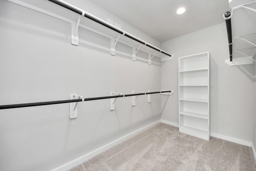 Walk-in closet that epitomizes luxury and practicality. This generously sized space features built-in shelving, offering abundant room for impeccable organization. High ceilings and recessed lighting create a bright and welcoming ambiance. Sample photo of completed home with similar floor plan. Actual colors and selections may vary.