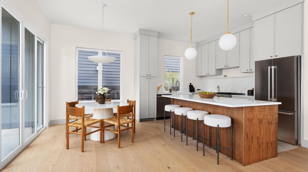 Kitchen featuring stainless steel appliances, white cabinetry, decorative light fixtures, light wood-type flooring, and recessed lighting