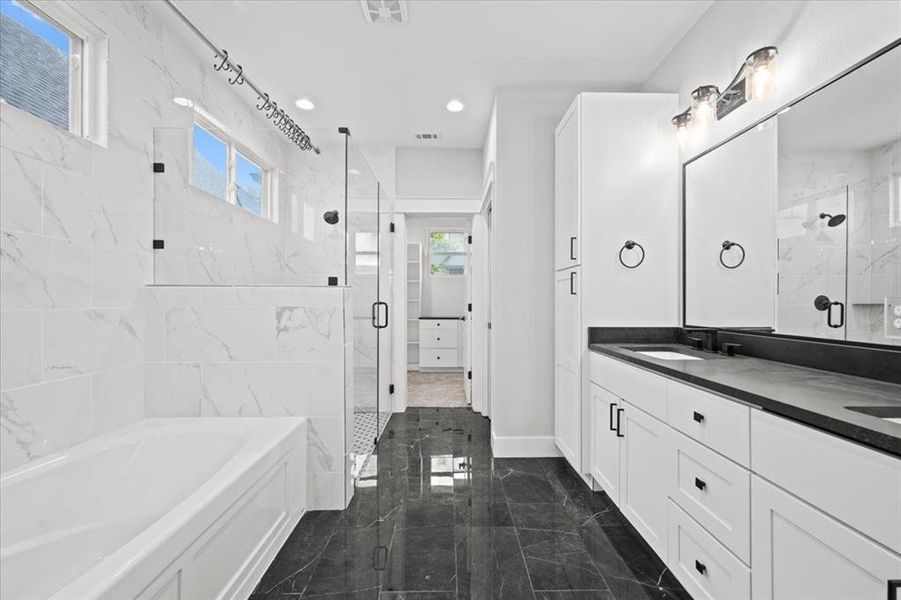 Bathroom featuring marble tiled flooring, a marble finish shower, a bath, double vanity, and recessed lighting