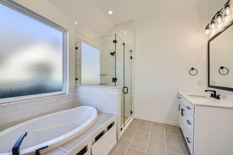 Bathroom with vanity, tile patterned floors, vaulted ceiling, and shower with separate bathtub