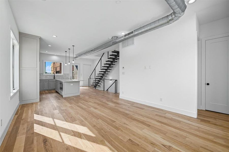 Unfurnished living room featuring recessed lighting, light wood-style flooring, and stairway