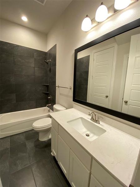 Bathroom featuring vanity, shower / bath combination, and dark tile patterned floors Bathroom featuring vanity, shower / bath combination, and dark tile patterned floors