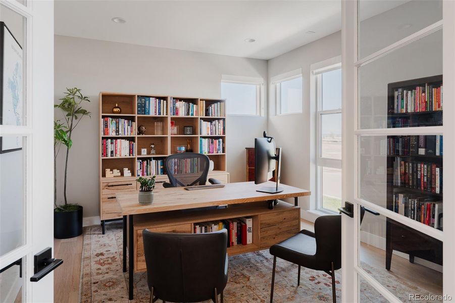 A main level home office, set behind modern double glass doors, offers an intellectual sanctuary that fosters focus and productivity, ideal for those seeking a sublime workspace at home.