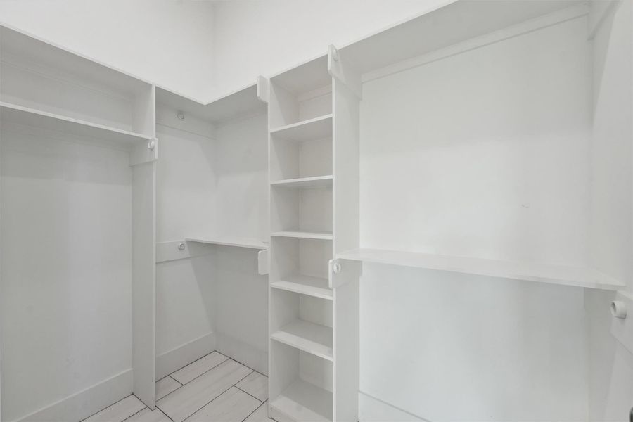 Spacious walk-in closet with built-in shelving and hanging space for organized storage. Spacious walk-in closet with built-in shelving and hanging space for organized storage.