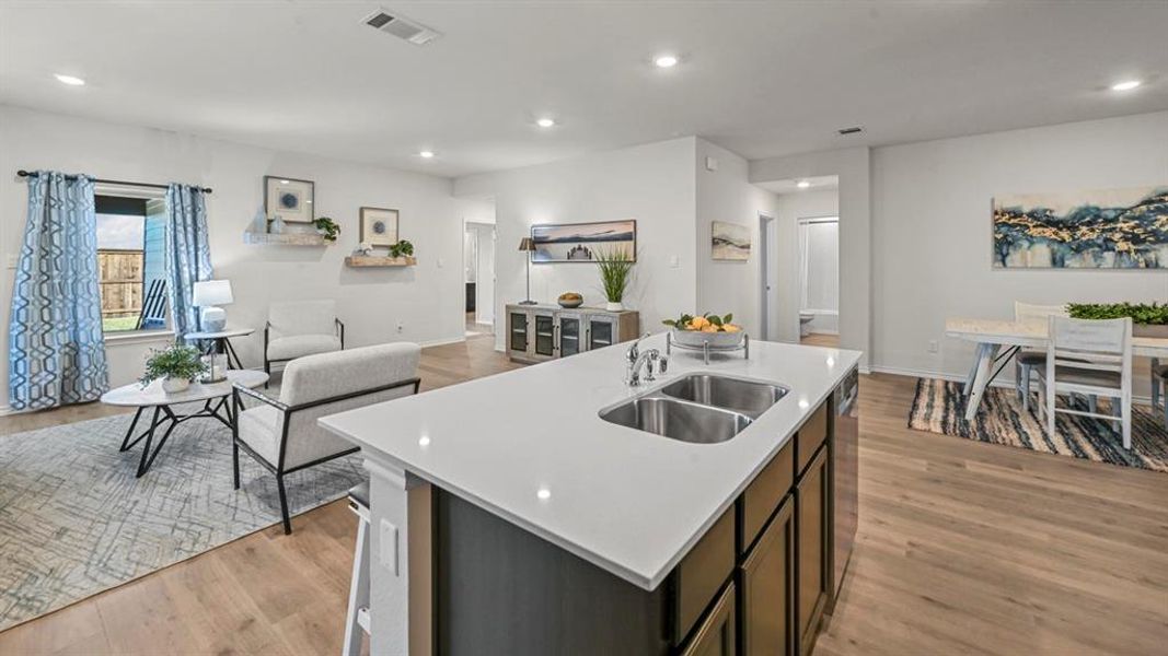 Kitchen with open floor plan, a center island with sink, light wood-style flooring, recessed lighting, and dishwasher