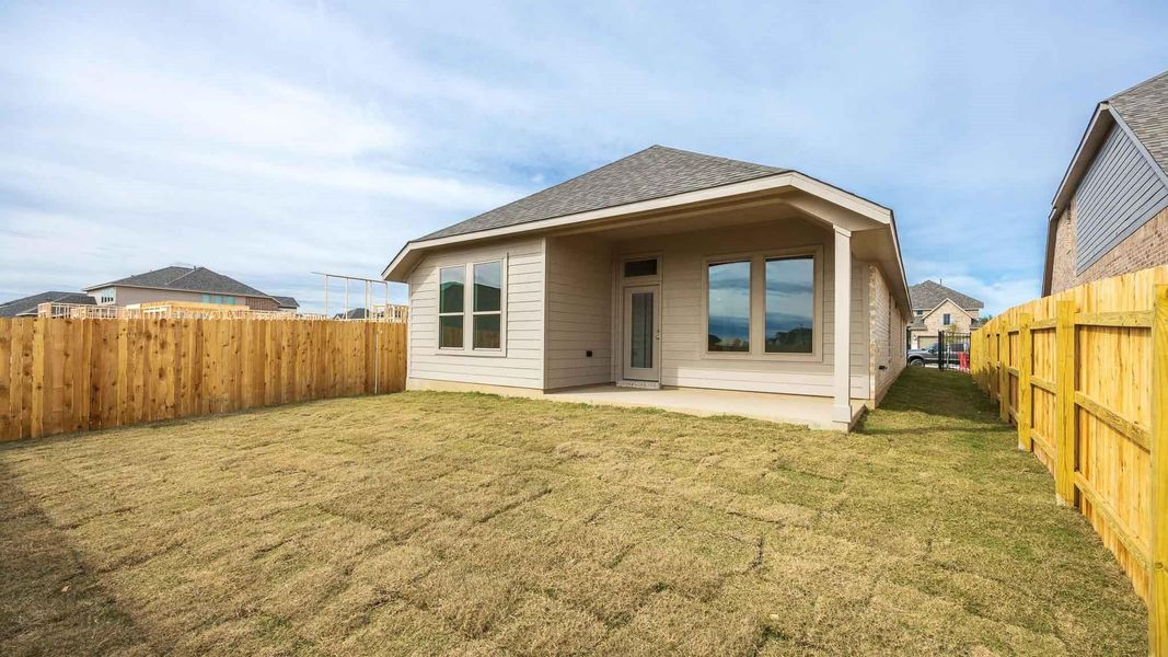 Back of house featuring a lawn and a patio area