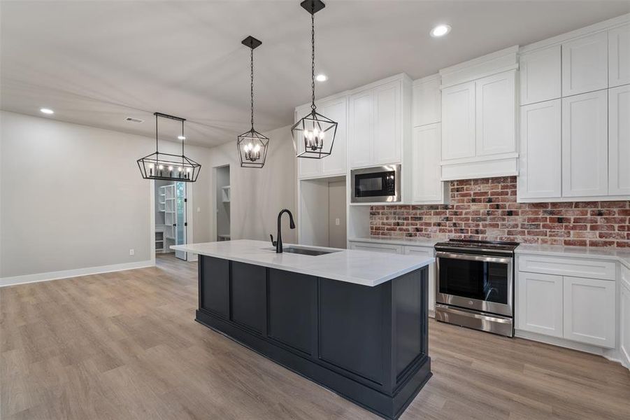 A Peek into the Butler's Pantry on the far left wall, Lantern Chandeliers over the Island and the Dining Area. New Stainless Appliances...