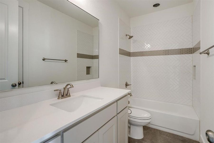 Full bathroom featuring vanity, tiled shower / bath, and toilet