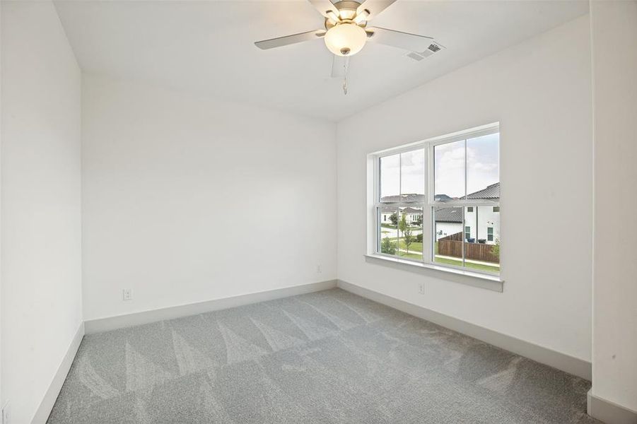 Bright room featuring a large window, neutral gray carpet, white walls, and a ceiling fan with integrated lighting Bright room featuring a large window, neutral gray carpet, white walls, and a ceiling fan with integrated lighting