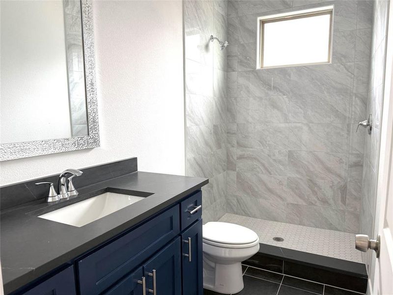 Full bath with vanity, toilet, tile patterned flooring, and a tile shower