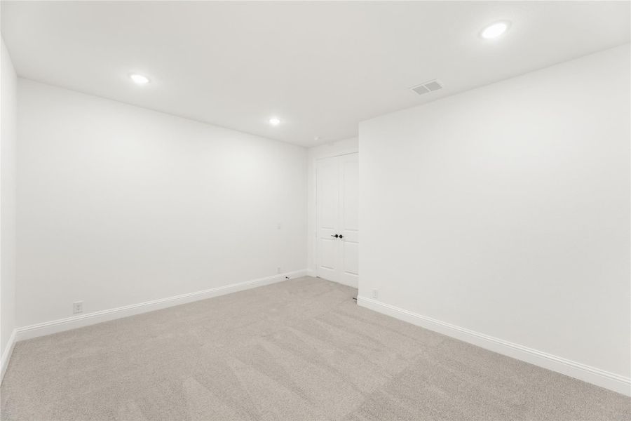 Empty room with white walls, gray carpet, recessed lighting, and a white door Empty room with white walls, gray carpet, recessed lighting, and a white door