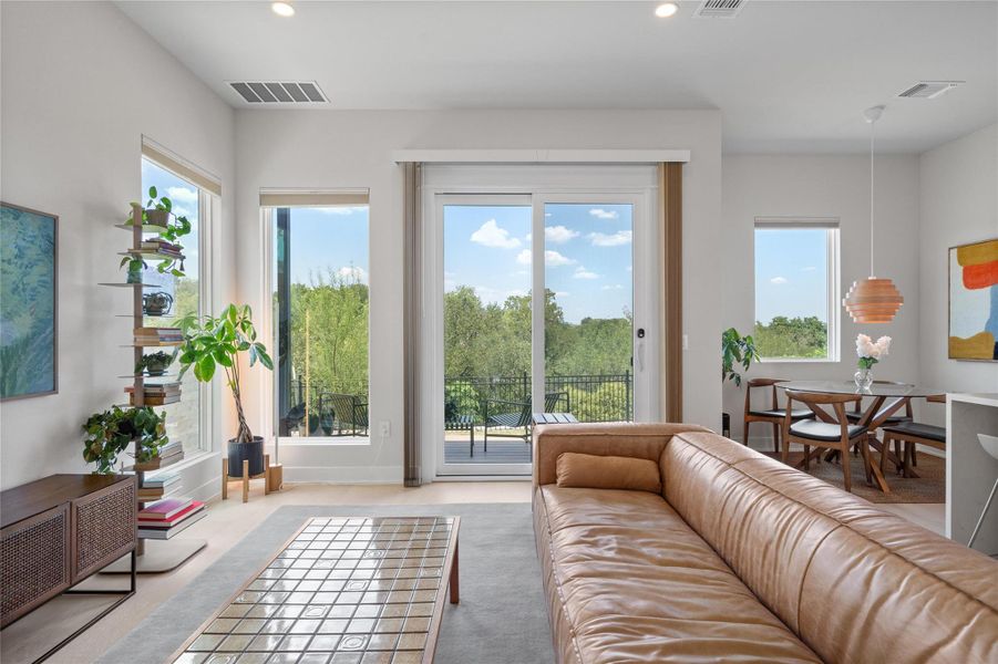 A spacious living area with abundant natural light transitions seamlessly to an outdoor balcony offering verdant views. A spacious living area with abundant natural light transitions seamlessly to an outdoor balcony offering verdant views.