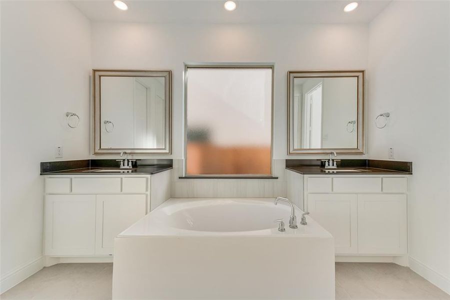 Bathroom with tile patterned flooring, a tub, and vanity