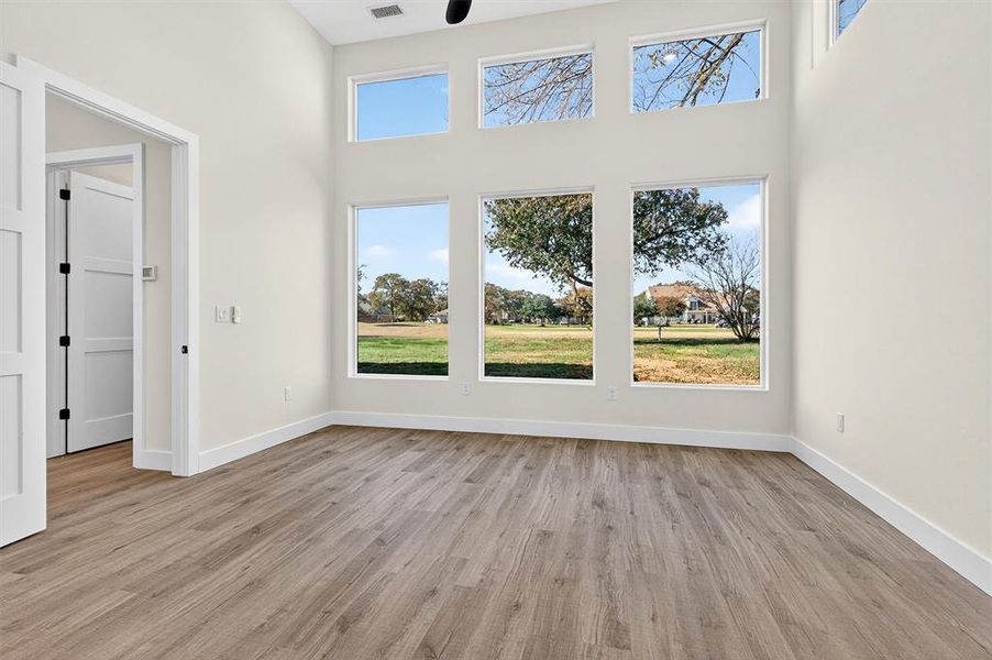 Unfurnished living room with light wood-style floors and a towering ceiling