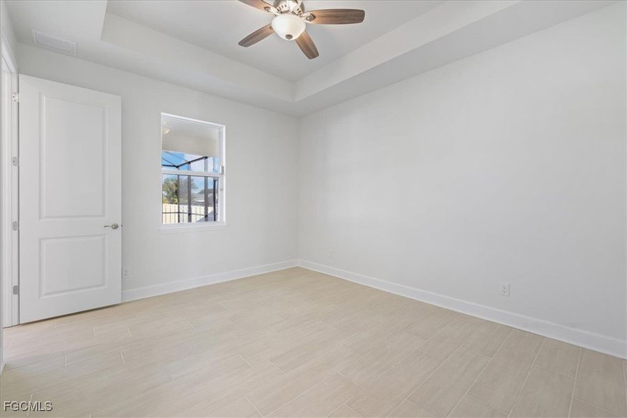 Unfurnished room with a raised ceiling, ceiling fan, and wood tiled floors Unfurnished room with a raised ceiling, ceiling fan, and wood tiled floors
