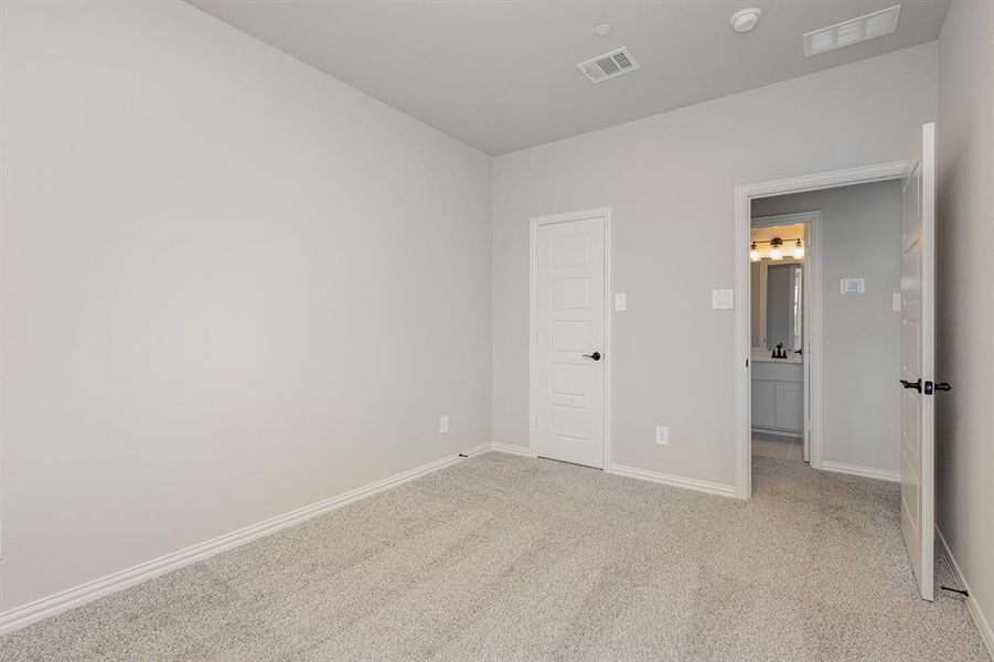 Unfurnished bedroom with light carpet and baseboards