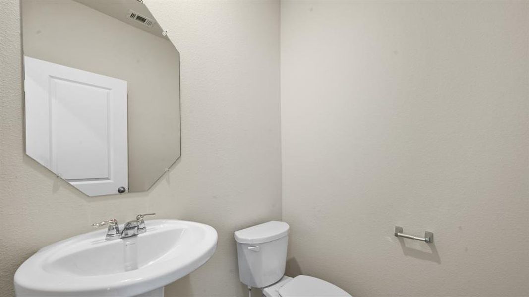 Pedestal sink with chrome faucet hardware, paired with a geometric wall mirror