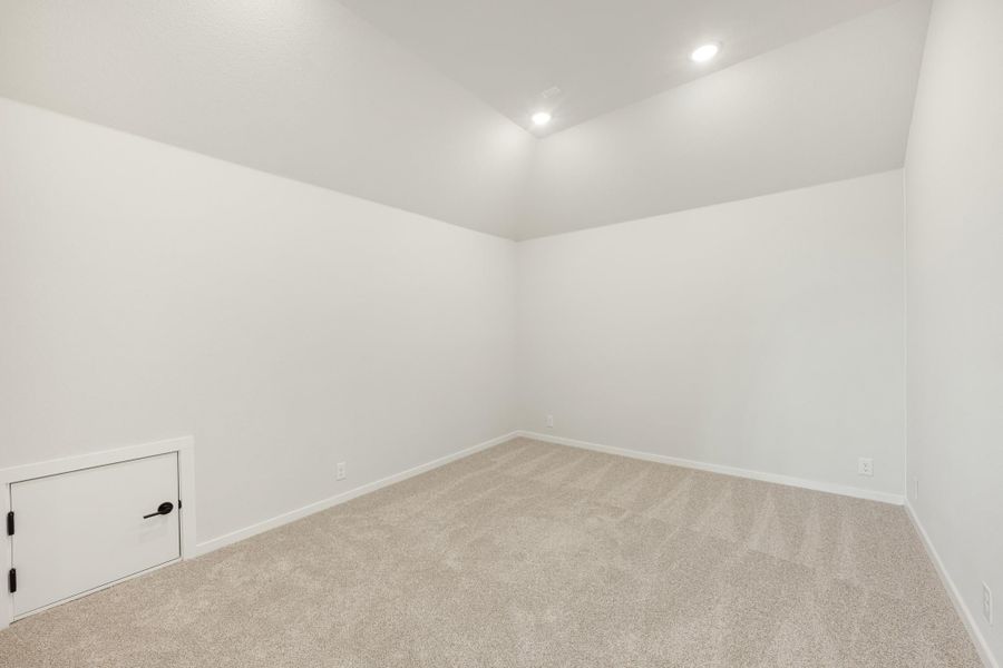 Empty room with white walls, beige carpet, recessed lighting, and small access door at floor level