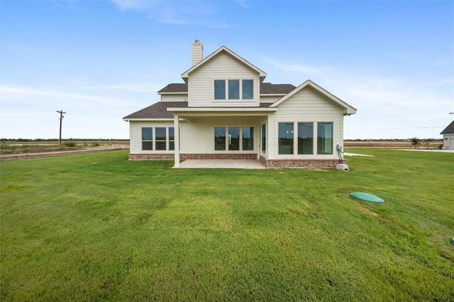Back of property featuring roof with shingles, a patio area, a yard, a chimney, and brick siding Back of property featuring roof with shingles, a patio area, a yard, a chimney, and brick siding