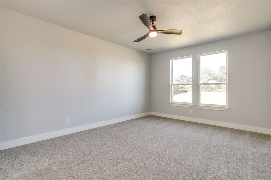 Empty room featuring light colored carpet and a ceiling fan
