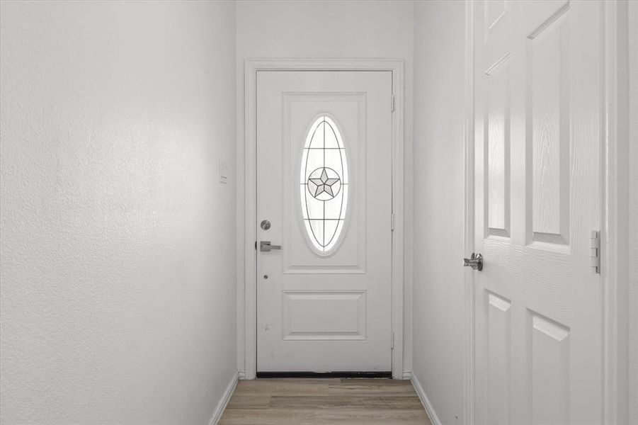 Doorway to outside with light wood finished floors and baseboards