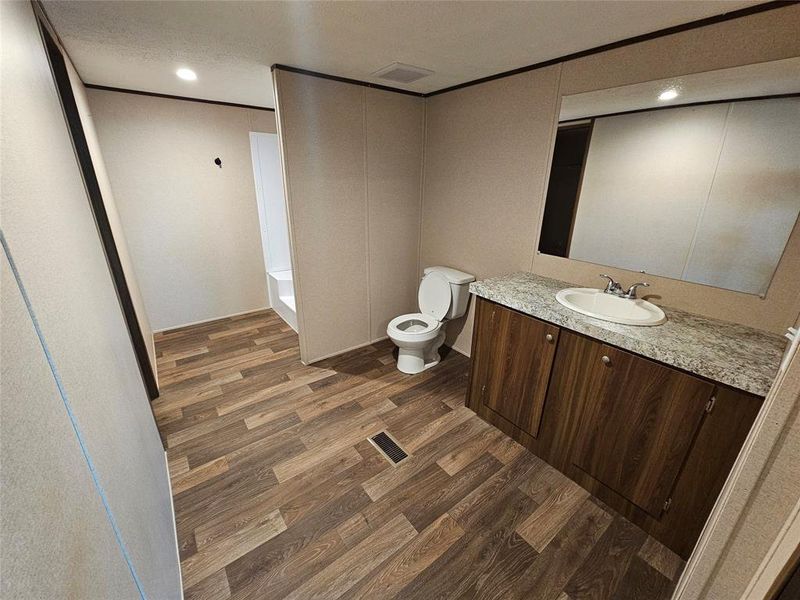 Full bathroom featuring dark wood-type flooring, vanity, recessed lighting, and a tub to relax in Full bathroom featuring dark wood-type flooring, vanity, recessed lighting, and a tub to relax in