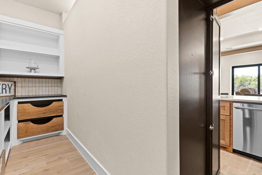 Hallway featuring light wood finished floors, a textured wall, and baseboards Hallway featuring light wood finished floors, a textured wall, and baseboards