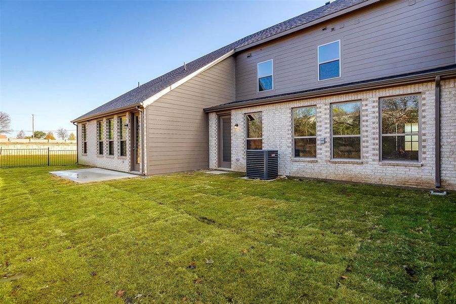 Back of house featuring cooling unit, a patio, and a lawn