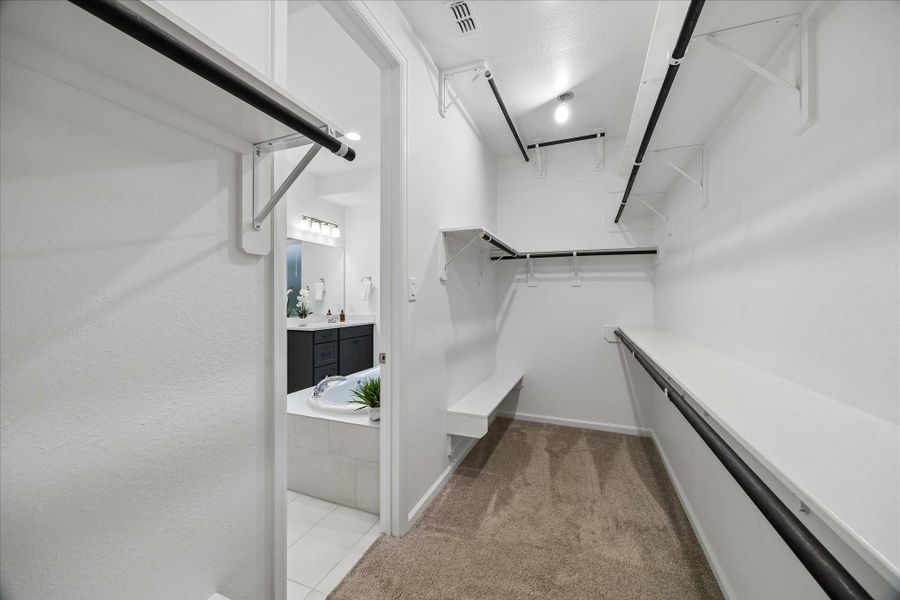 Shop until you drop! This deep walk-in closet can take it. Making use of every inch, notice the high hanging bars for clothes and the low shelving for shoes, bags, and more.