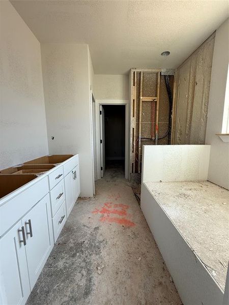 Full bathroom featuring a textured ceiling, unfinished concrete flooring, walk in shower, and a textured wall