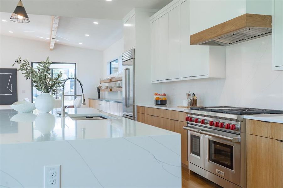 Kitchen featuring premium Wolf and Subzero appliances, light hardwood / wood-style flooring, light stone countertops, custom cabinets, and premium range hood