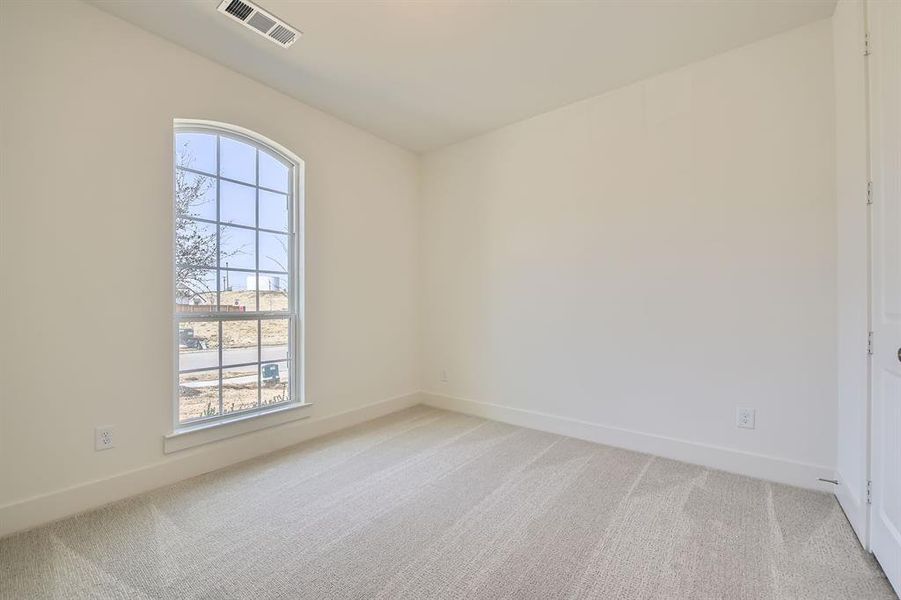 Empty room with visible vents, light colored carpet, and a healthy amount of sunlight