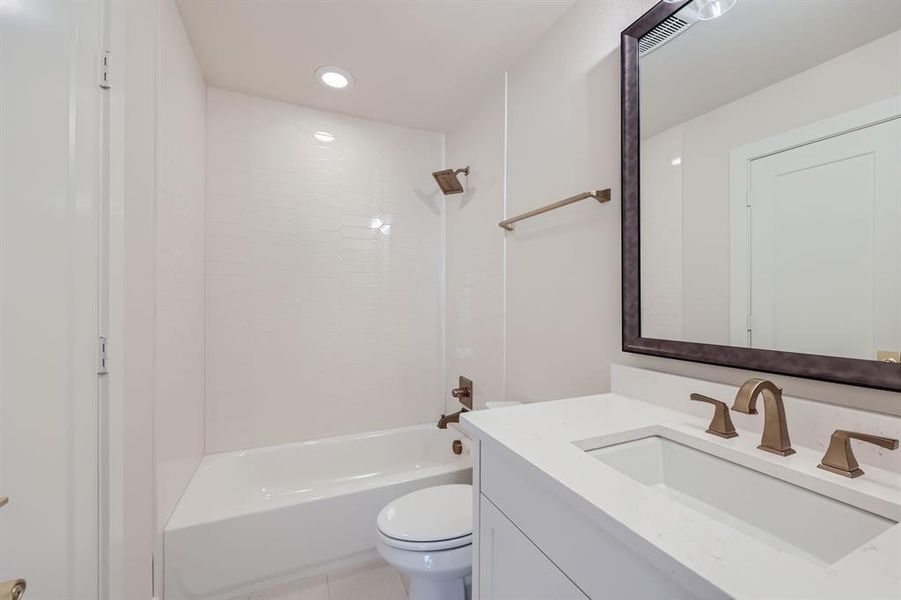 Full bathroom with vanity, toilet, tile patterned floors, and washtub / shower combination