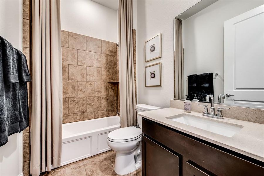 Bathroom with shower / bath combo with shower curtain, vanity, and light tile patterned floors
