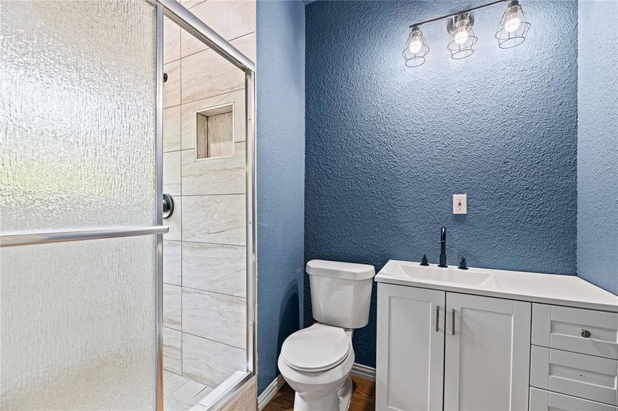 Bathroom with an enclosed shower, toilet, and vanity Bathroom with an enclosed shower, toilet, and vanity