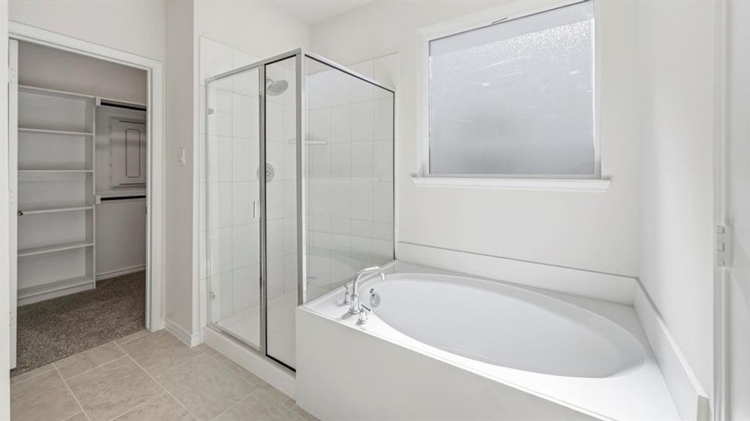 Full bathroom with a bath, a shower stall, light tile patterned floors, and a spacious closet Full bathroom with a bath, a shower stall, light tile patterned floors, and a spacious closet