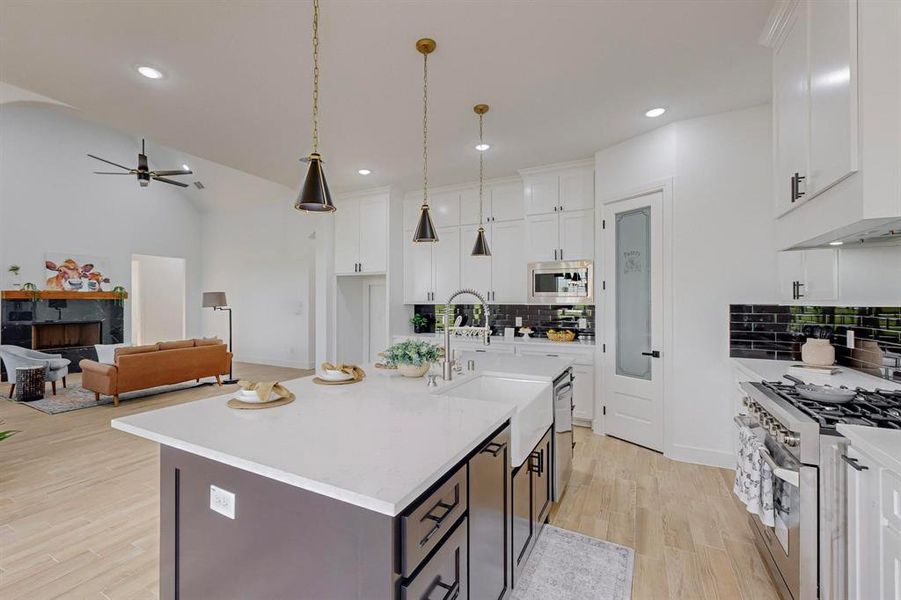 Kitchen with light hardwood / wood-style flooring, tasteful backsplash, stainless steel appliances, sink, and a kitchen island with sink