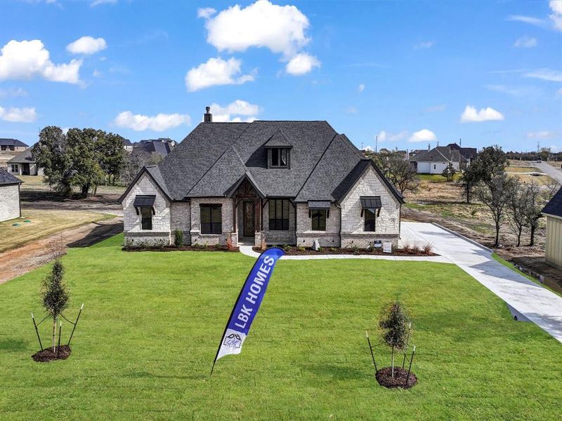 French country inspired facade with a front lawn